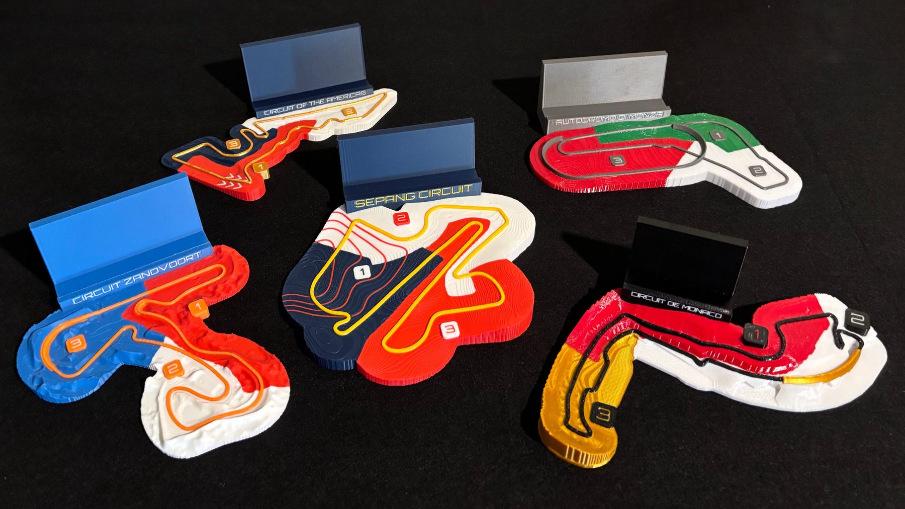 Monaco, Monza, Zandvoort, Circuit of the Americas, Sepang relief maps with their nameplate stands, on a black mat